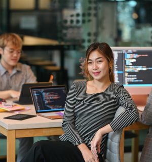 Young female software developer sitting in start up office with co working atmosphere.