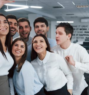 Fooling around fot the camera. Young team making selfie in classical clothes in the modern good lighted office.